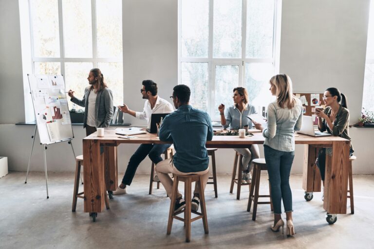 A group of people surround a table looking at a white board